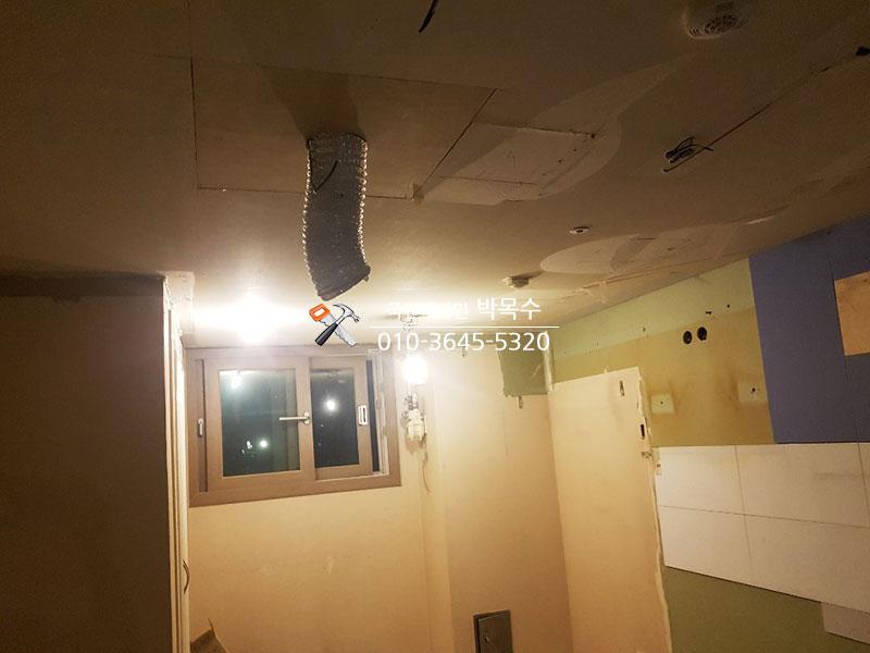 천장 파이프와 흰색 타일, 파란 패널이 보이는 작업 공간