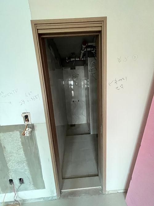 기존 나무 문틀과 배관이 노출된 시공 전 복도