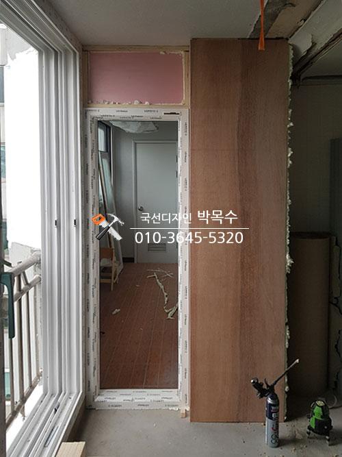 분홍색 마감 표면과 보드 구조물이 설치 중인 창호 주변