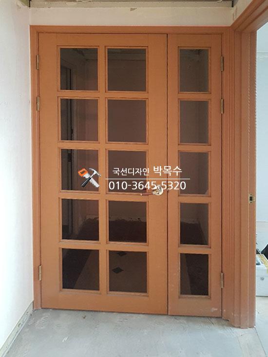 나무색 도어와 유리 패널로 마감된 현관문