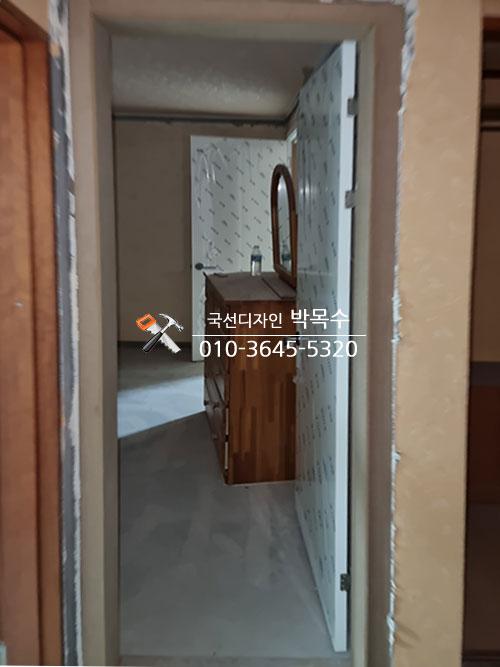흰색 도배지와 목재 수납장이 배치된 복도