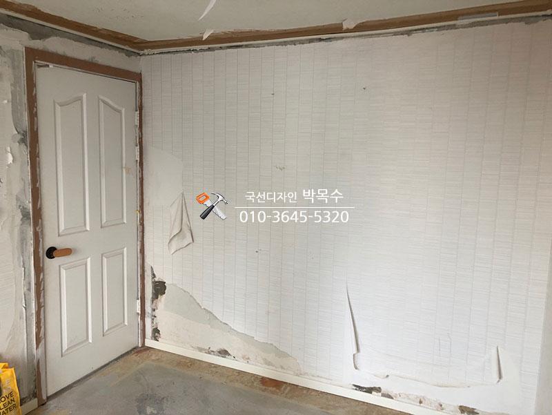 흰색 여닫이문과 부분적으로 붙은 벽지