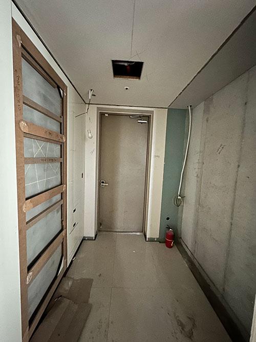 배관이 노출되어 있고 도배지가 부분적으로 남은 복도