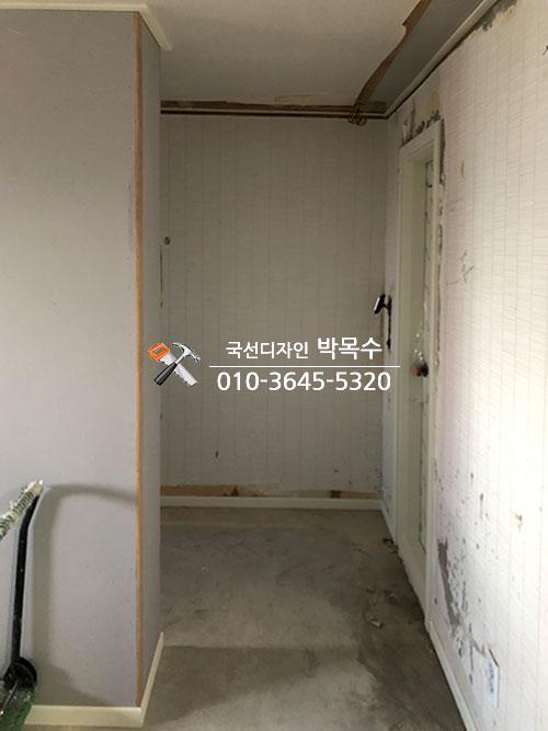 도배지가 부분적으로 남은 텅 빈 복도 공간