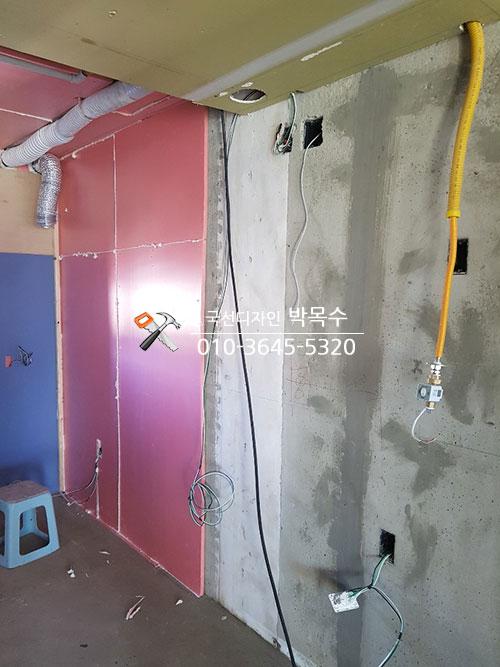 배관이 노출된 천장과 분홍색·파란색 벽면의 모습