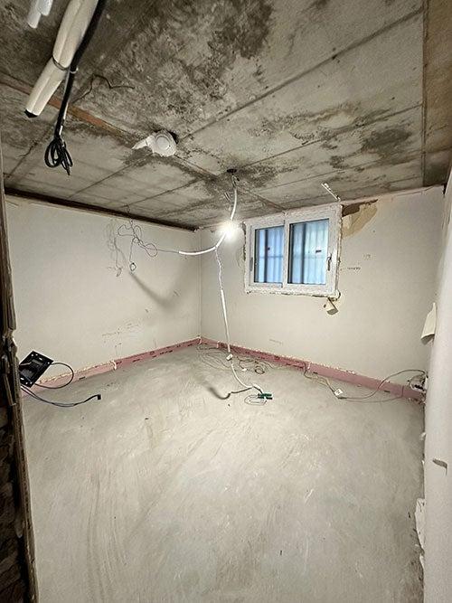 노출 콘크리트 천정과 핑크색 베이스보드가 보이는 방