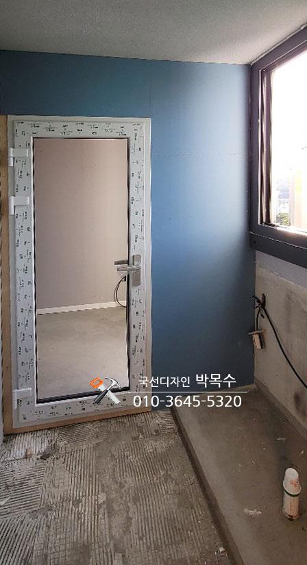 파란 벽면과 도어 프레임이 보이는 철거 후의 실내 공간