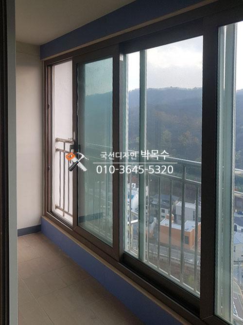 검은색 프레임의 창호와 정돈된 베란다 바닥 타일