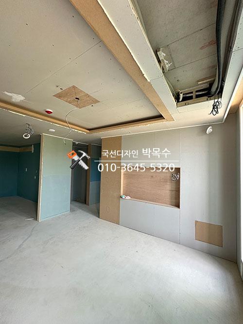 배관이 노출된 천장 아래 벽면 패널을 설치하는 과정