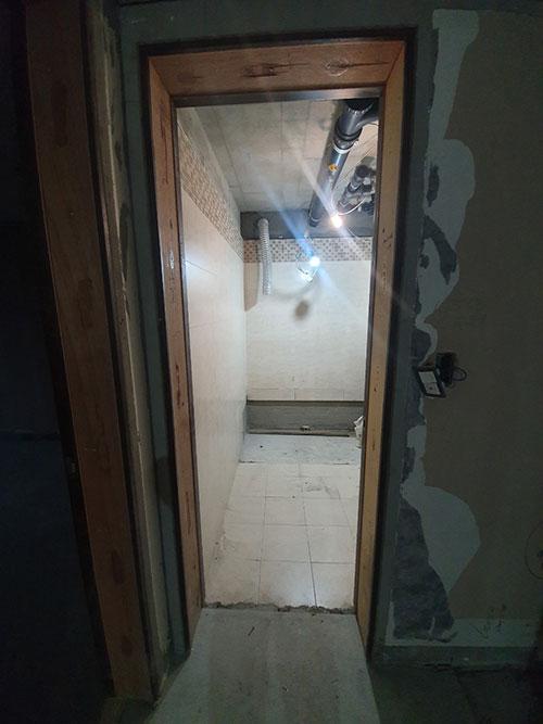 배관이 노출된 복도 천장과 나무 문틀
