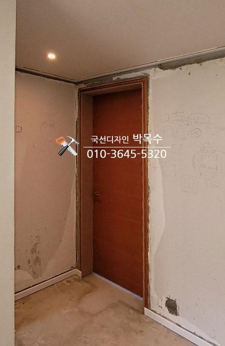갈색 문과 천장 조명이 설치된 벽면 마감 전 모습