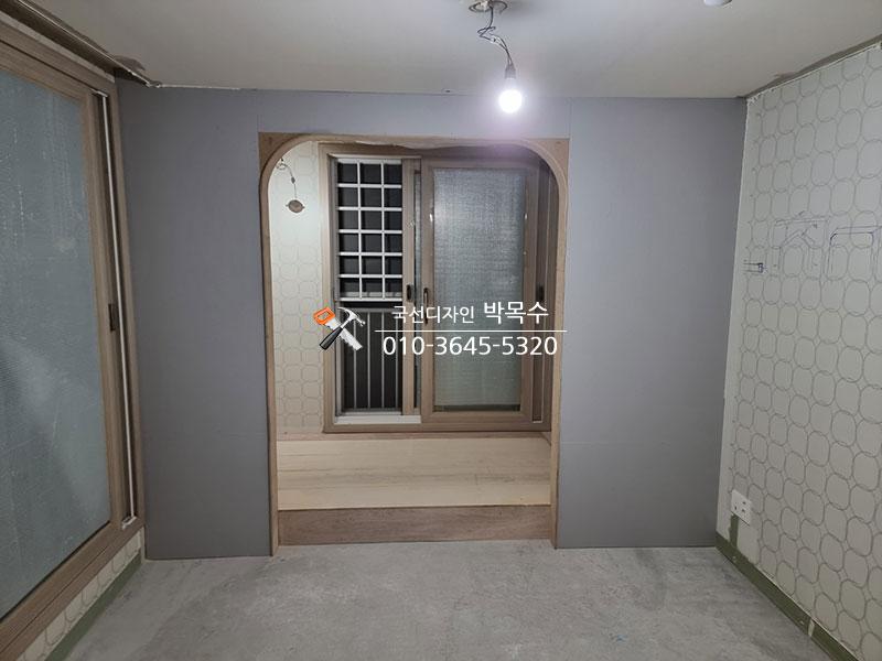 회색 벽면과 목재 테두리가 어우러진 현관 입구
