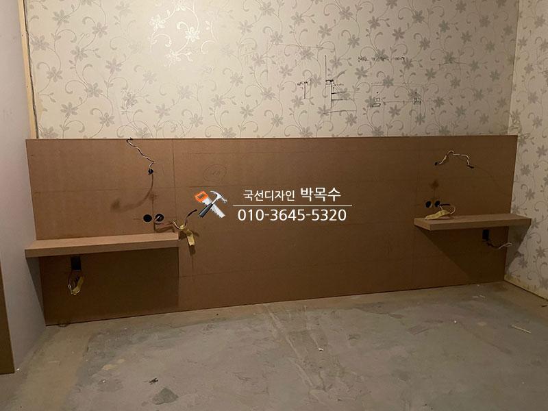 베이지색 보드로 조성된 침대 헤드와 선반 구조물