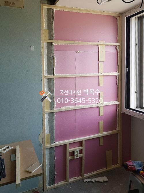 목재 프레임 사이에 설치된 분홍색 보온재와 흙바닥