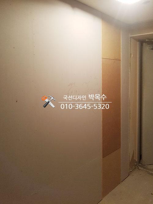 흰 벽과 베이지색 목재 패널이 나란히 이어진 복도