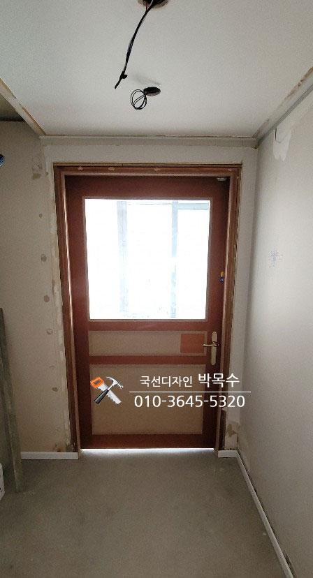 상단 유리 패널이 있는 갈색 도어와 노출 전선이 보이는 복도