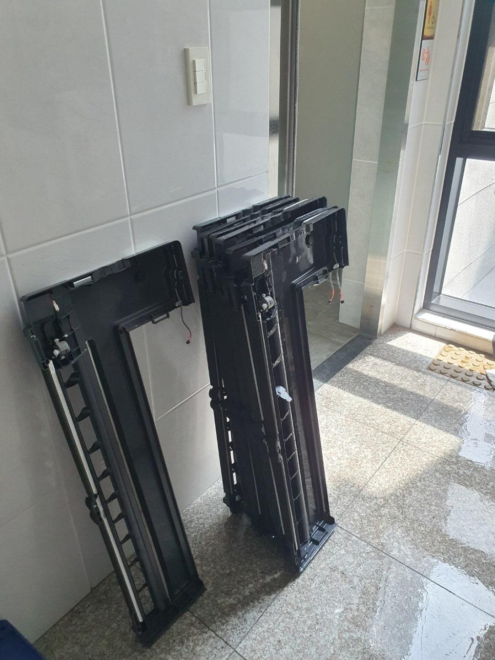 현관 벽면에 기대어 있는 검은색 플라스틱 수납 부품들