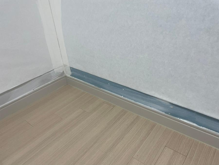 벽지와 바닥 사이 파란색 접착제가 보이는 구석