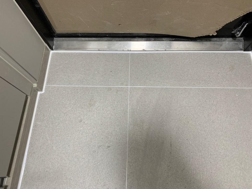 금속 베이스보드와 회색 타일 바닥의 접합 부분
