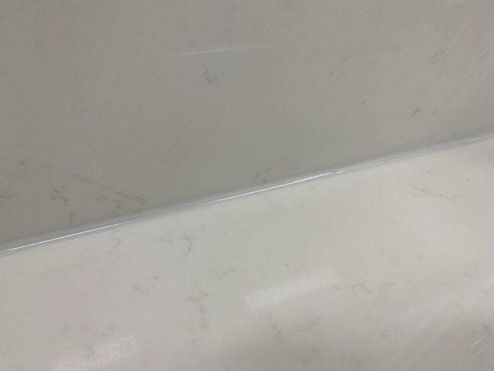 흰색 마감된 벽과 바닥의 접합부에 투명한 실리콘 씰러가 있는 공간