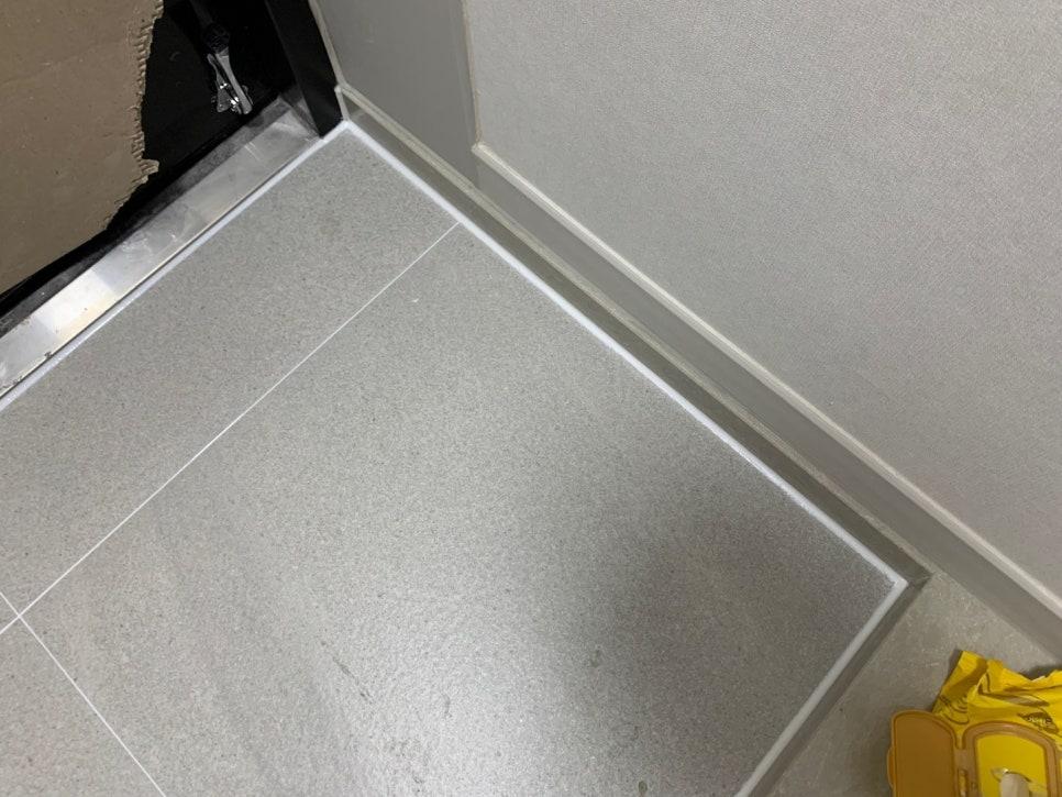 베이지색 벽면과 흰색 걸레받이가 있는 회색 타일 바닥