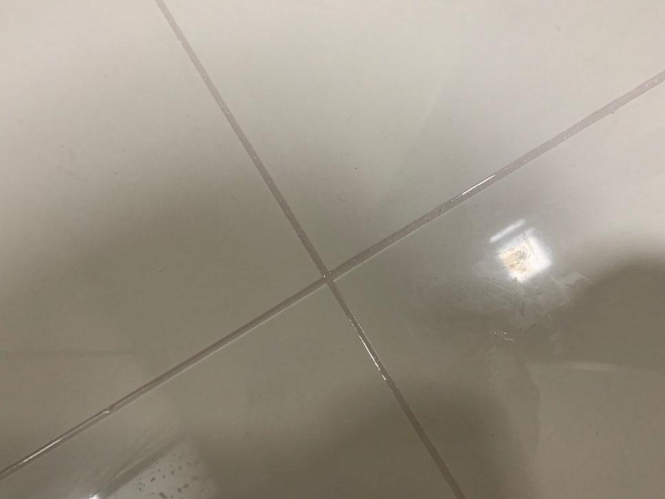 흰색 타일 벽면과 바닥 사이의 틈새 작업 과정