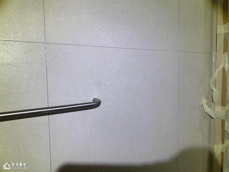 마스킹 테이프로 보양 작업 중인 흰색 타일 벽면