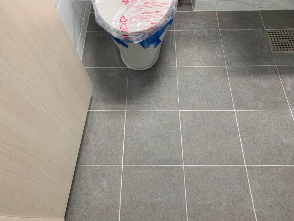 회색 타일 바닥과 흰색 세면대가 보이는 화장실