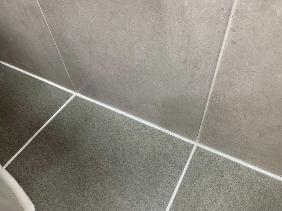 회색 타일 벽면과 바닥 접합부의 흰색 셔딩 작업