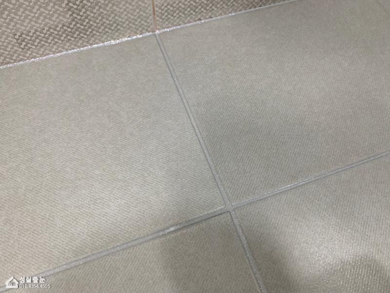 베이지색 타일 틈새의 시멘트 제거 작업