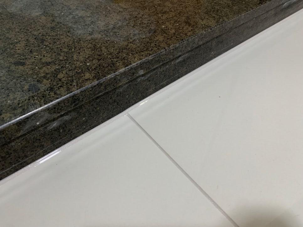 검은색 석재 상판과 흰색 타일 바닥의 접합부 시공
