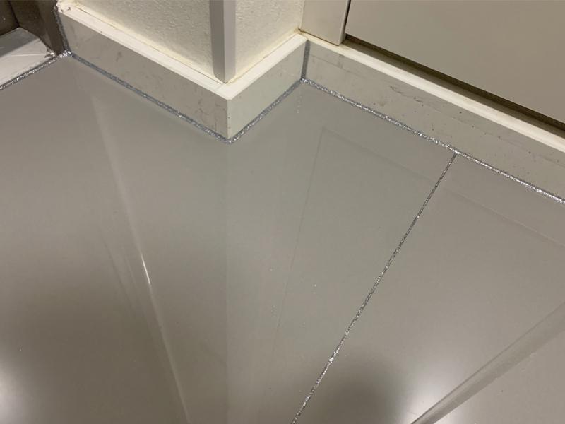 실버 컬러로 채워진 타일 틈새와 흰색 베이스보드