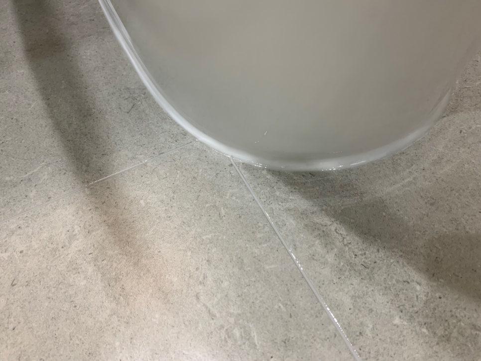 회색 타일 바닥 위 투명 원통형 용기가 보이는 시공 모습