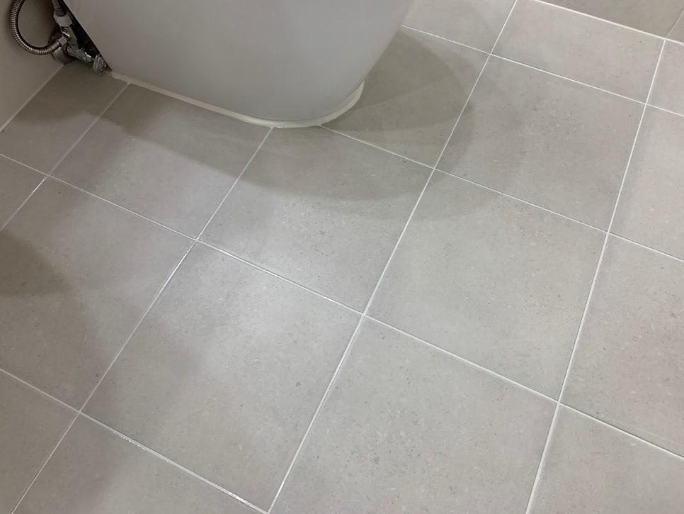 회색 타일 바닥과 세면대 하단 배관이 보이는 시공 과정