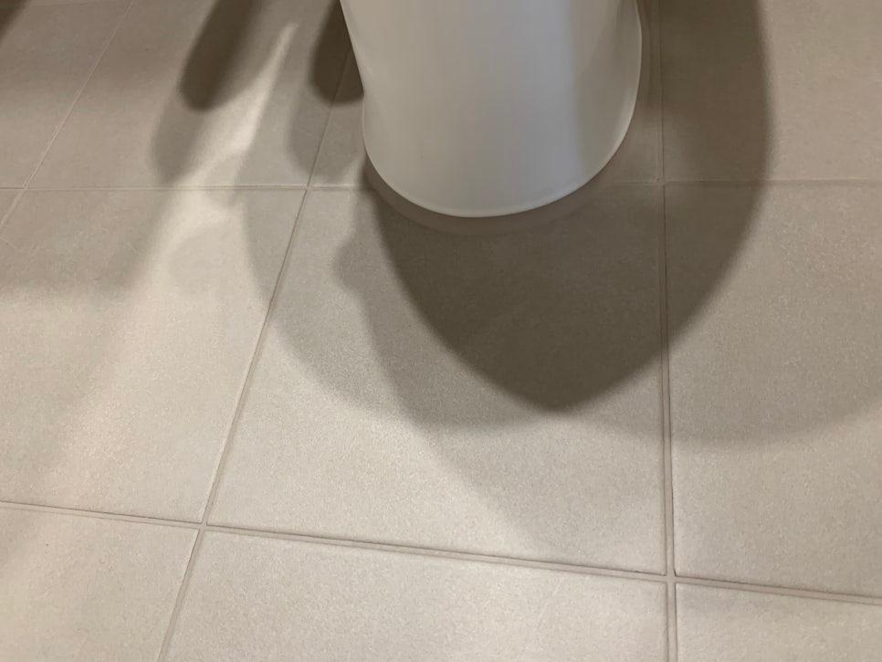 흰색 타일 바닥과 세면대 그림자가 보이는 공간