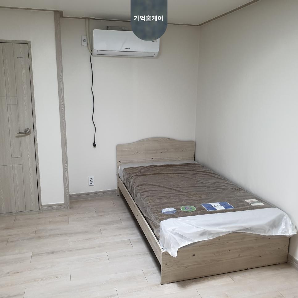 베이지색 헤드보드와 브라운 커버의 침대가 놓인 방입니다.