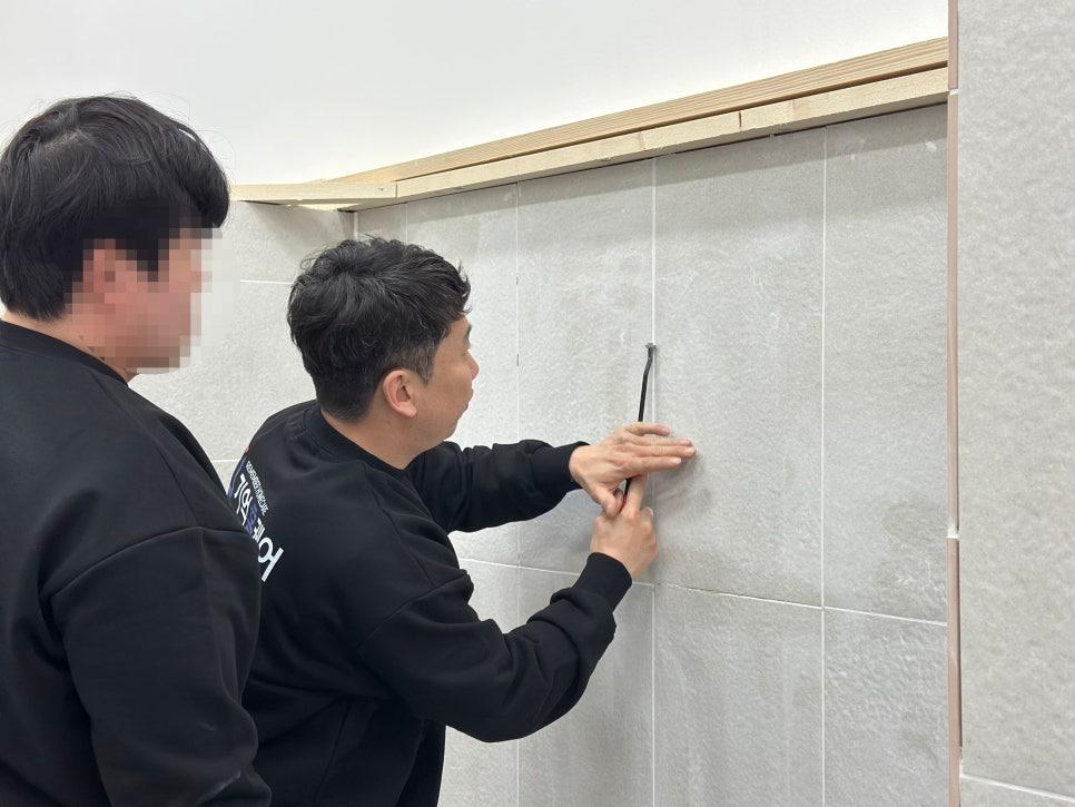 회색 타일 벽면에 타일을 부착하는 작업 모습