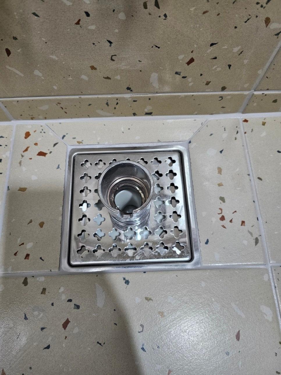 금속 배수구 뚜껑과 베이지색 타일 바닥