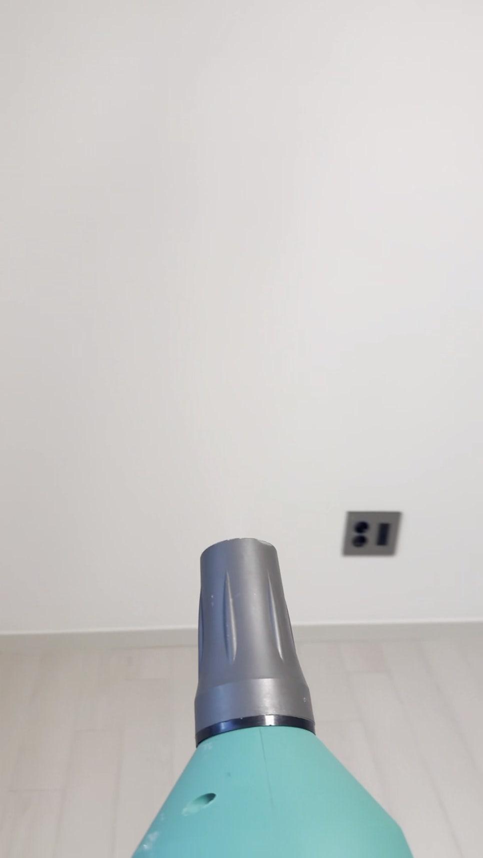 흰 벽면 소켓과 바닥 위 연두색 도구 끝부분