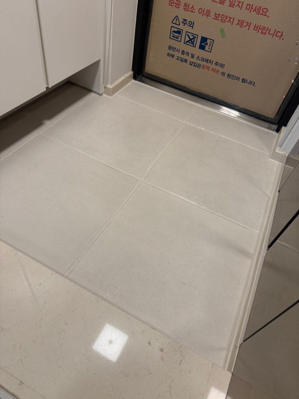 흰색 타일로 깔끔하게 마감된 현관 바닥