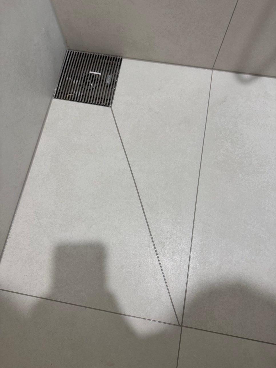 검은색 라인 배수구가 있는 흰색 타일 바닥