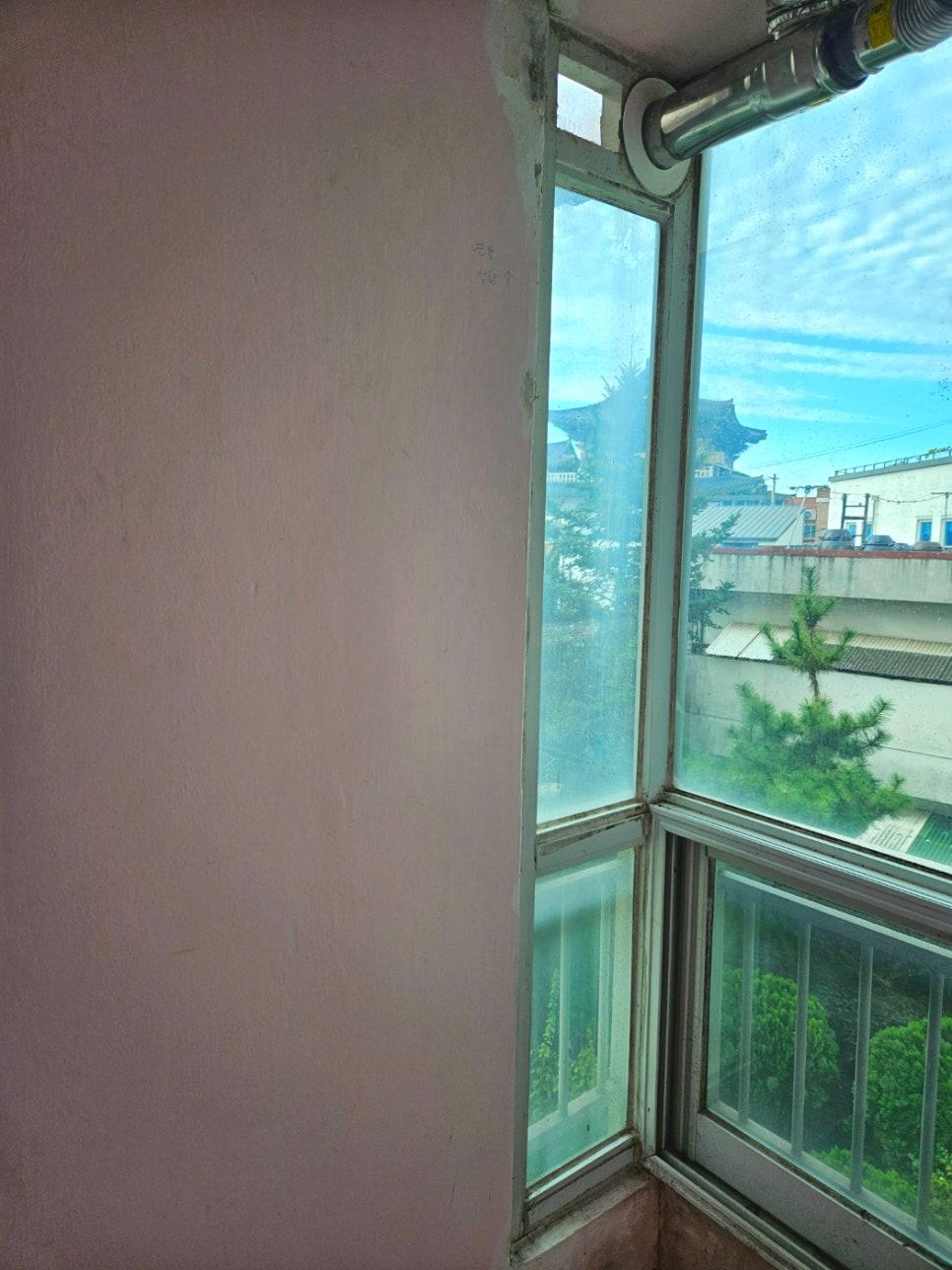 분홍색 벽면과 흰색 프레임의 창호 근접 샷