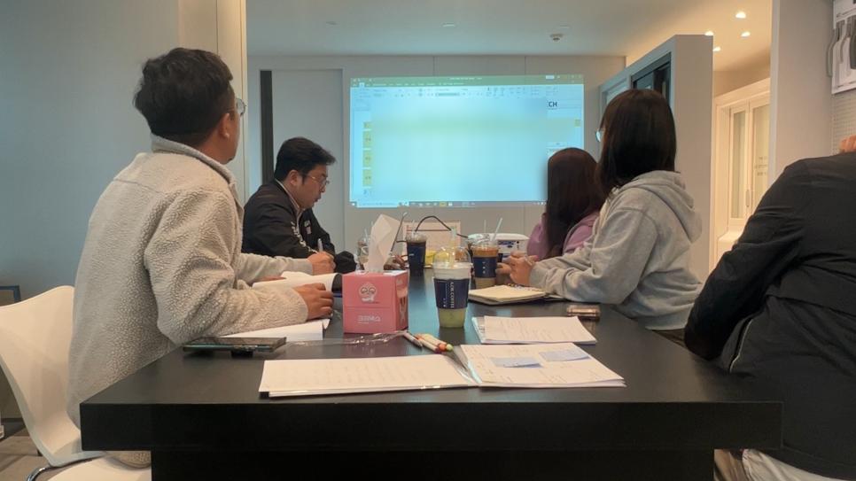 서류와 음료가 놓인 테이블과 프로젝터 화면