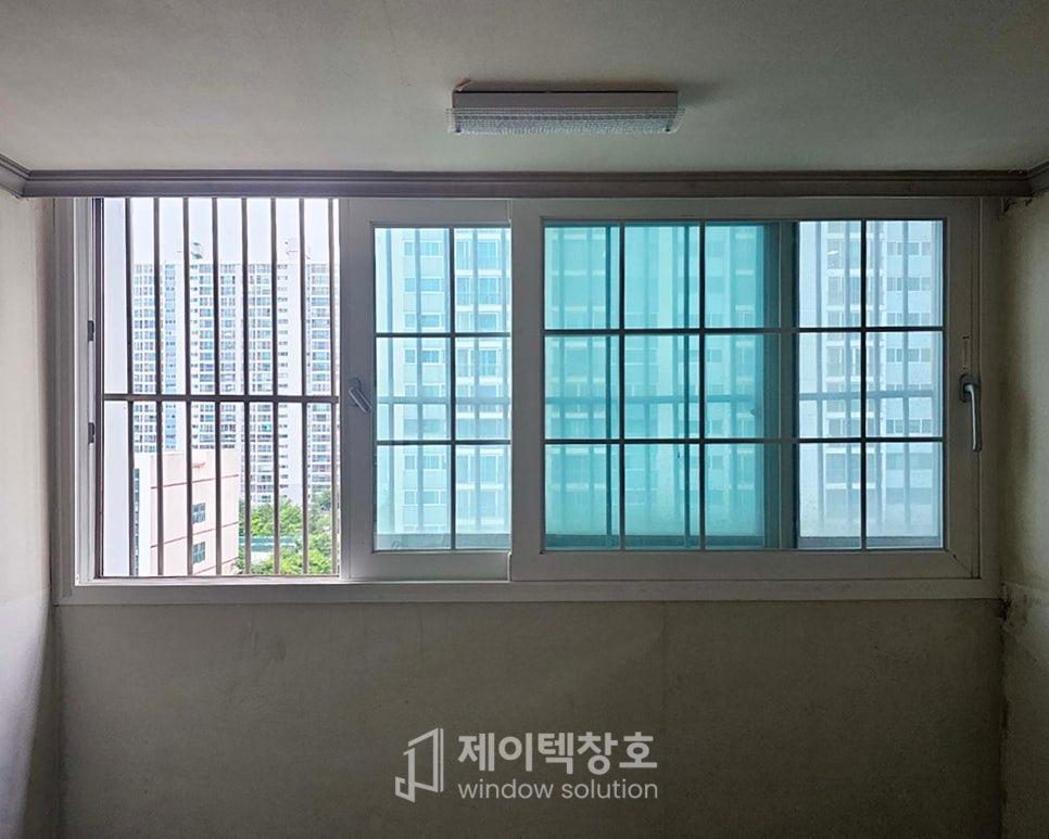 창호가 보이는 실내 공간, 창호는 세 개의 유리 패널로 구성되어 있으며 왼쪽 패널은 금속 격자로 보호되어 있고 중앙 및 오른쪽 패널은 투명 유리로 되어 있다. 창호 위쪽에는 조명 장치가 설치되어 있으며 벽은 벽지나