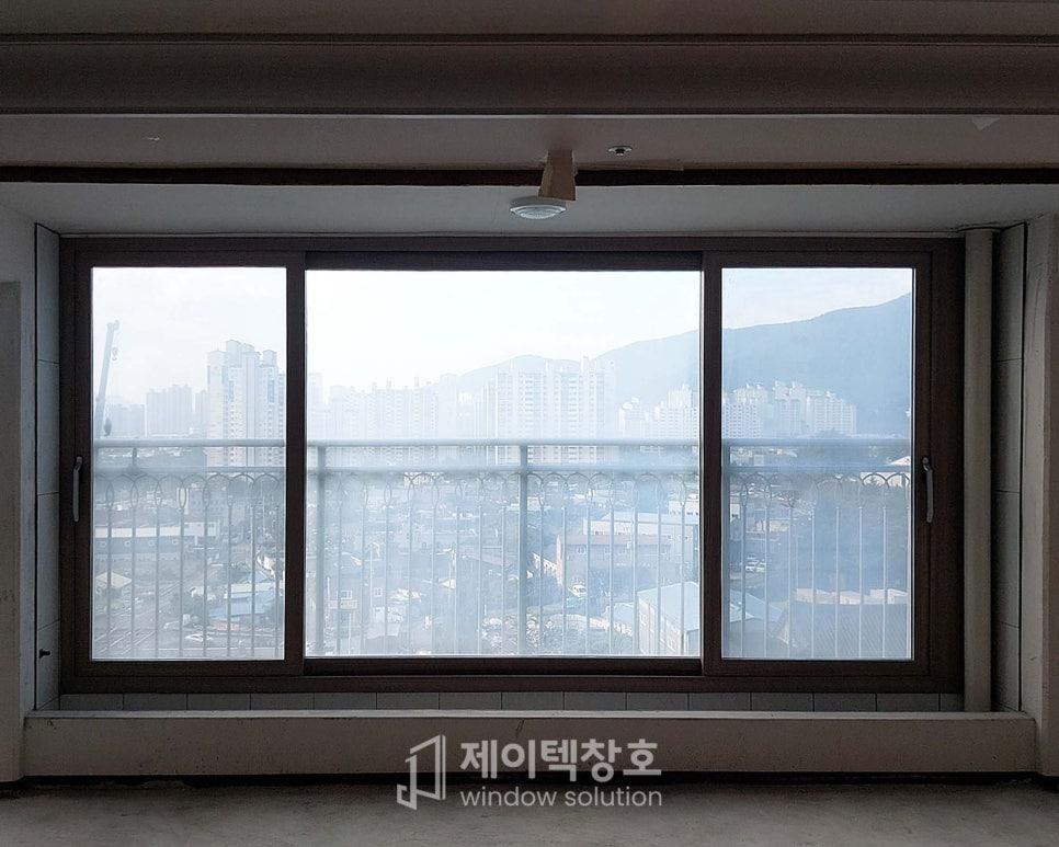 창호 외부로 도시 건물과 산이 보이는 시공 중인 실내 공간