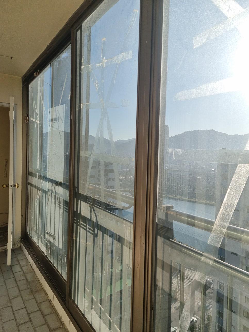 큰 유리창 너머로 외부 건물과 산이 보이는 발코니 전경