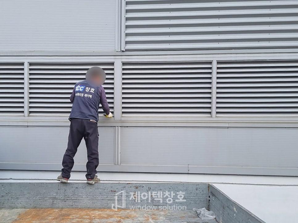 벽면에 금속 블라인드 창호를 설치 중인 작업 모습