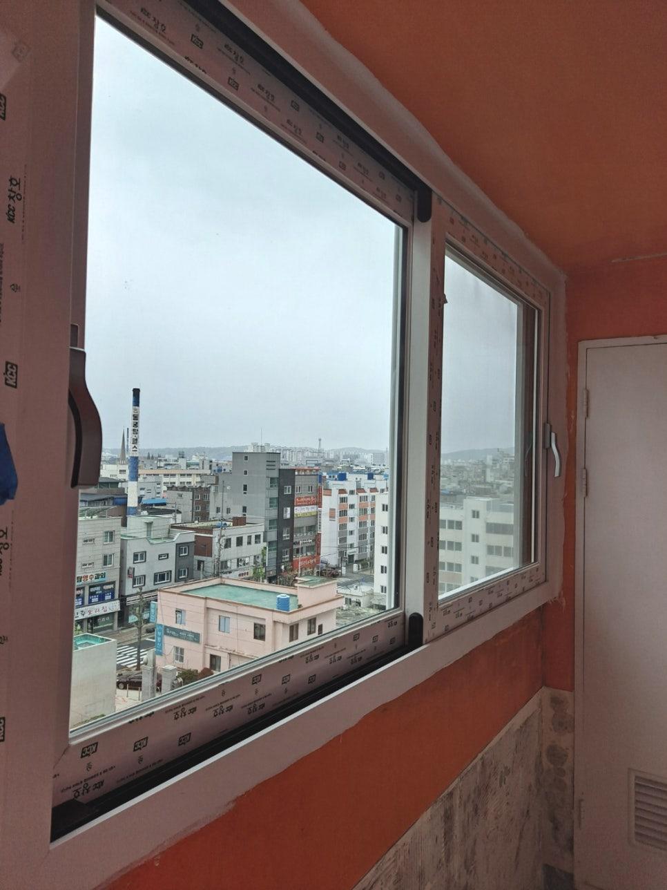 주황색 페인트 벽면과 흰색 창호 프레임 너머로 보이는 도시 풍경