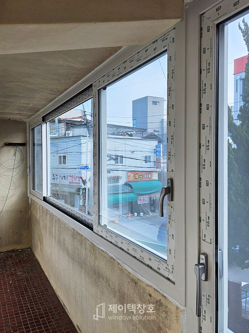 흰색 프레임 창호 너머로 상가가 보이는 모습