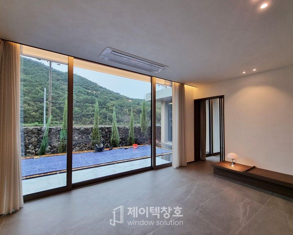넓은 유리 슬라이딩 도어를 통해 자연 풍경이 들어오는 거실